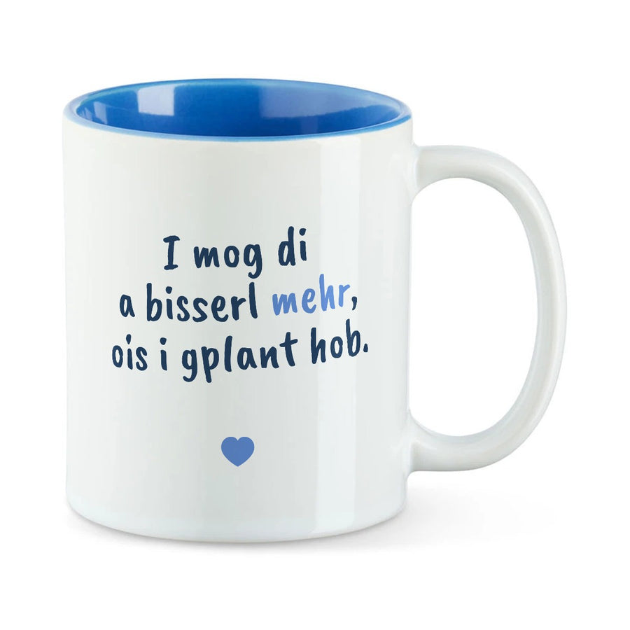 Weiße Tasse mit blauer Innenseite und dem bairischen Spruch „I mog di a bisserl mehr, ois i gplant hob.“ in Pinselschrift.