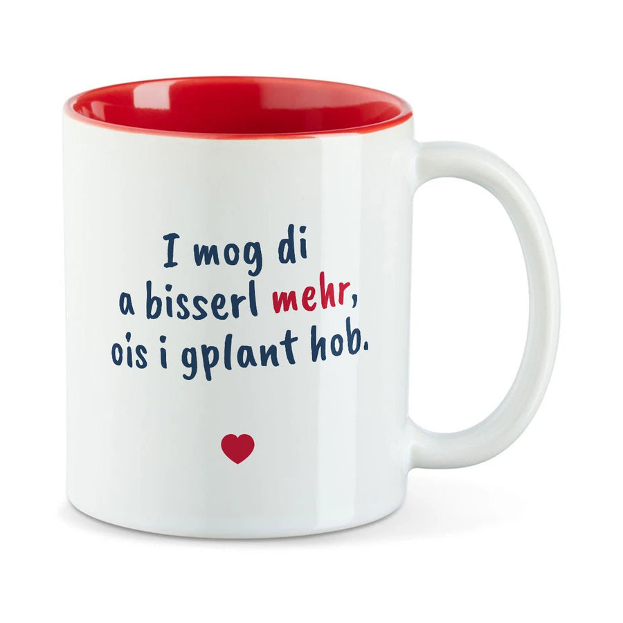 Weiße Tasse mit roter Innenseite und dem bairischen Spruch „I mog di a bisserl mehr, ois i gplant hob.“ in Pinselschrift.