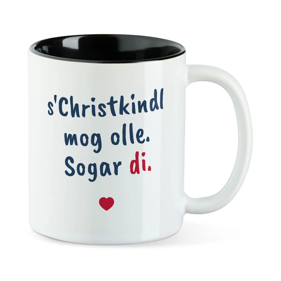 Weiße Tasse mit schwarzer Innenseite und dem bairischen Spruch „s'Christkindl mog olle. Sogar di.“ in Pinselschrift.