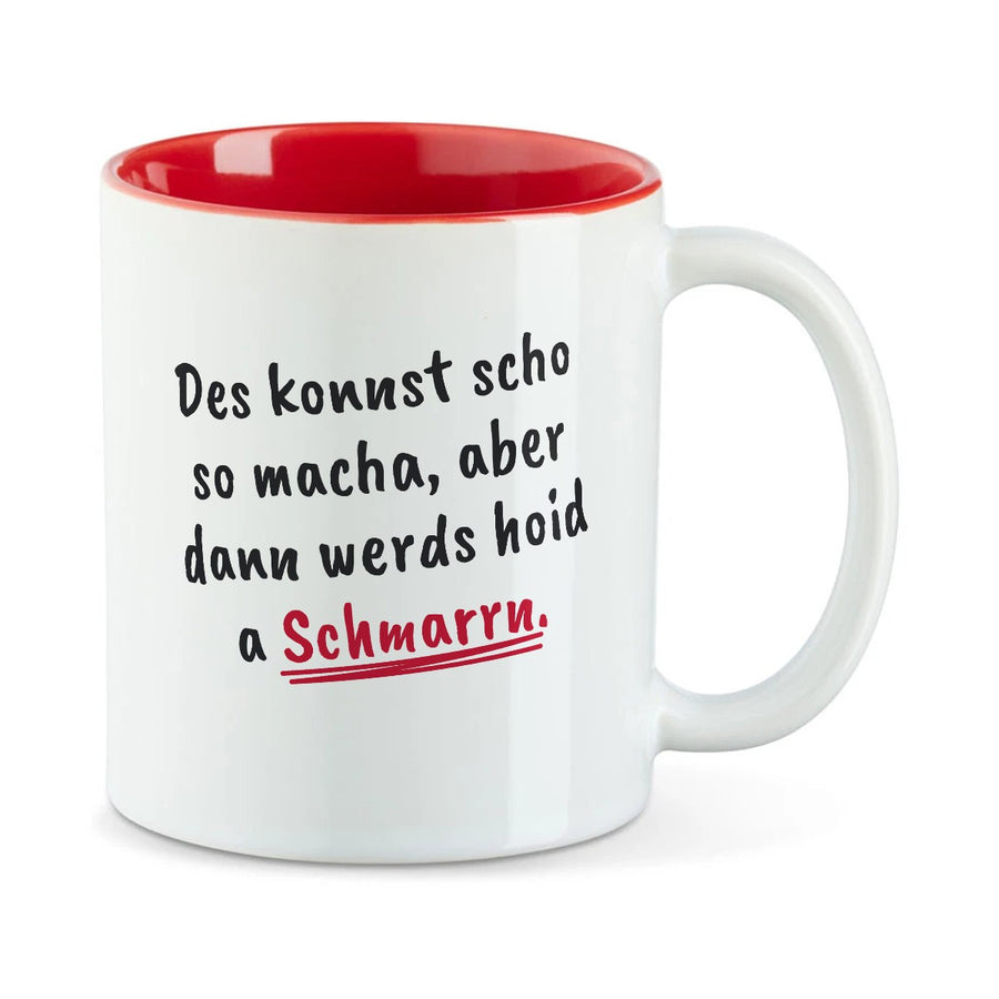 Weiße Tasse mit roter Innenseite und dem bairischen Spruch „Des konnst scho so macha, aber dann werds hoid a Schmarrn.“ in Pinselschrift.
