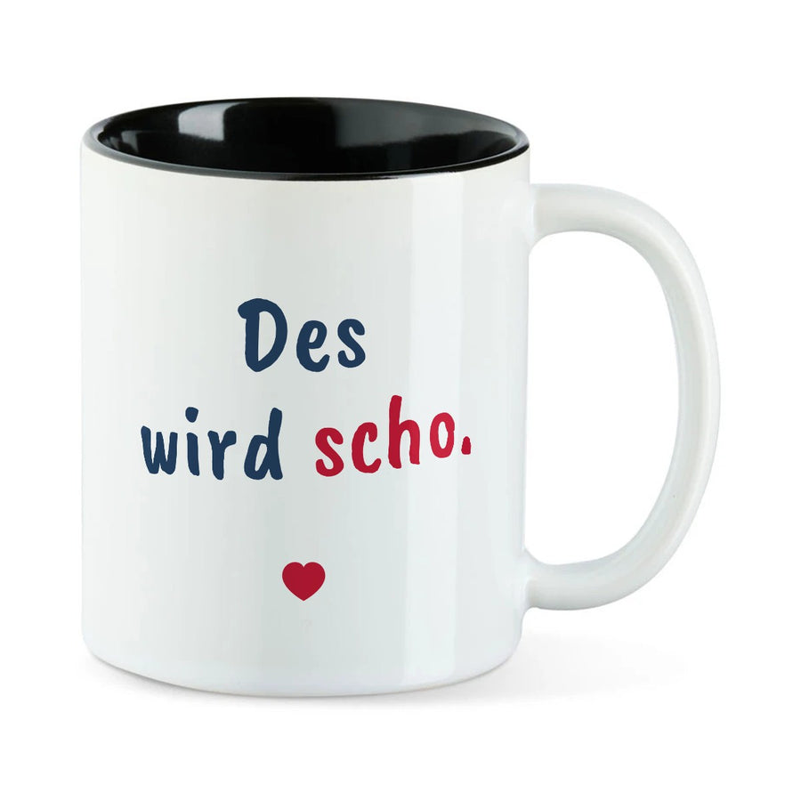 Weiße Tasse mit schwarzer Innenseite und dem bairischen Spruch „Des wird scho.“ in Pinselschrift.