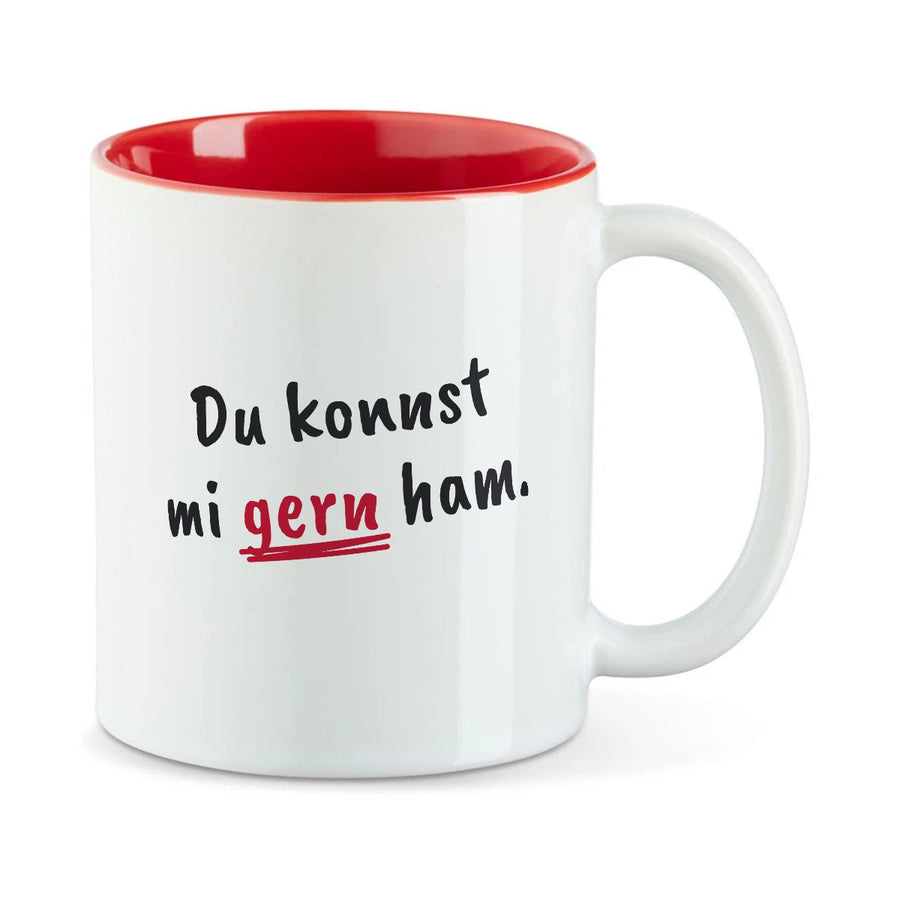 Weiße Tasse mit roter Innenseite und dem bairischen Spruch „Du konnst mi gern ham.“ in Pinselschrift.