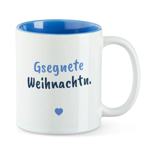 Weiße Tasse mit blauer Innenseite und dem bairischen Spruch „Gsegnete Weihnachtn.“ in Pinselschrift.