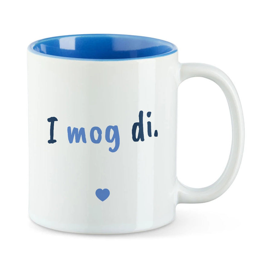 Weiße Tasse mit blauer Innenseite und dem bairischen Spruch „I mog di.“ in Pinselschrift.
