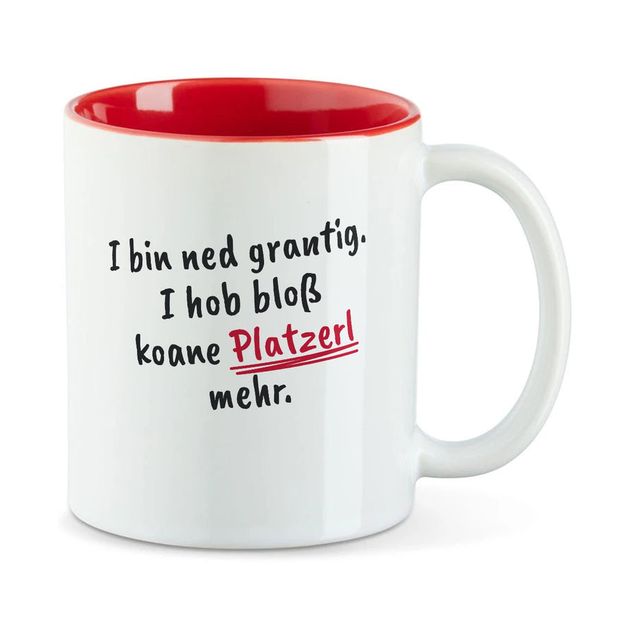 Weiße Tasse mit roter Innenseite und dem bairischen Spruch „I bin ned grantig. I hob bloß koane Platzerl mehr.“ in Pinselschrift.