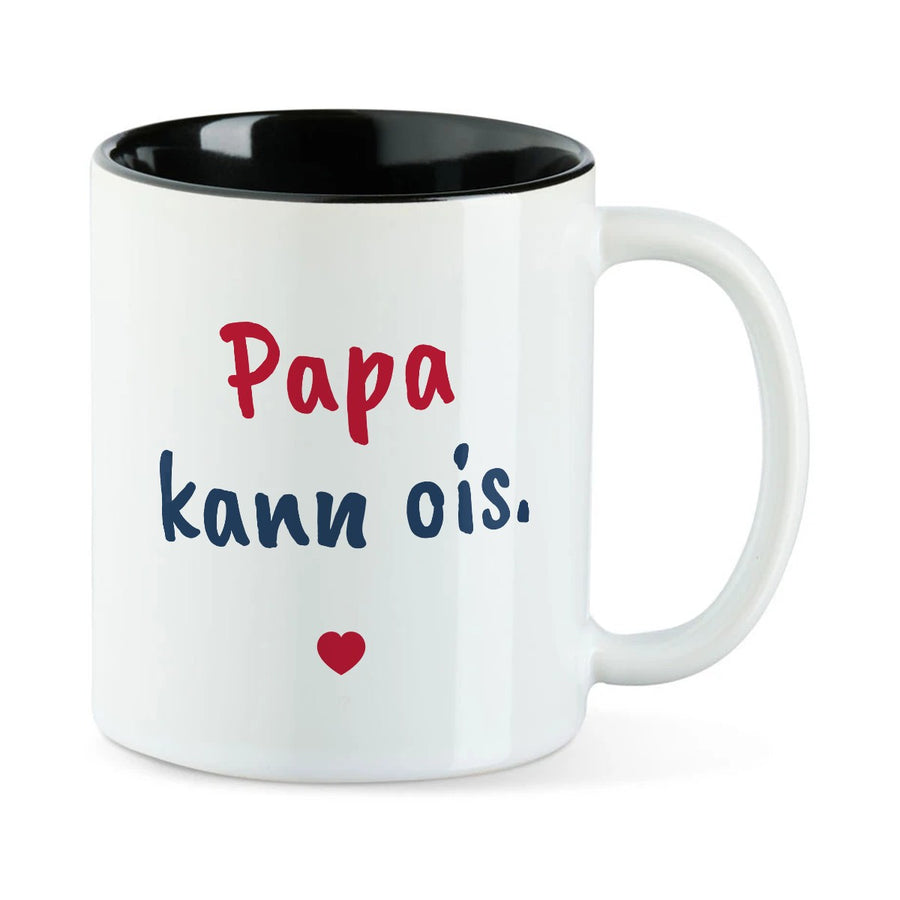 Weiße Tasse mit schwarzer Innenseite und dem bairischen Spruch „Papa kann ois.“ in Pinselschrift.