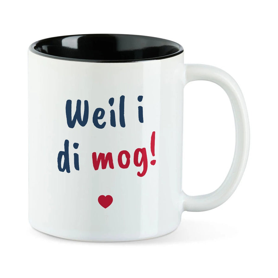 Weiße Tasse mit schwarzer Innenseite und dem bairischen Spruch „Weil i di mog!“ in Pinselschrift.