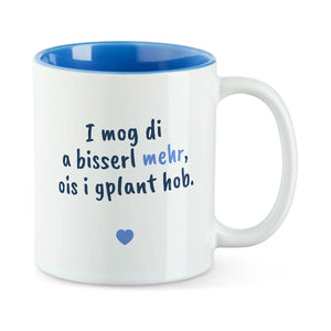 Weiße Tasse mit blauer Innenseite und dem bairischen Spruch „I mog di a bisserl mehr, ois i gplant hob.“ in Pinselschrift.