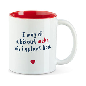 Weiße Tasse mit roter Innenseite und dem bairischen Spruch „I mog di a bisserl mehr, ois i gplant hob.“ in Pinselschrift.