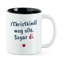Weiße Tasse mit schwarzer Innenseite und dem bairischen Spruch „s'Christkindl mog olle. Sogar di.“ in Pinselschrift.