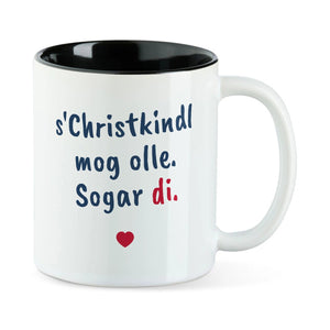 Weiße Tasse mit schwarzer Innenseite und dem bairischen Spruch „s'Christkindl mog olle. Sogar di.“ in Pinselschrift.