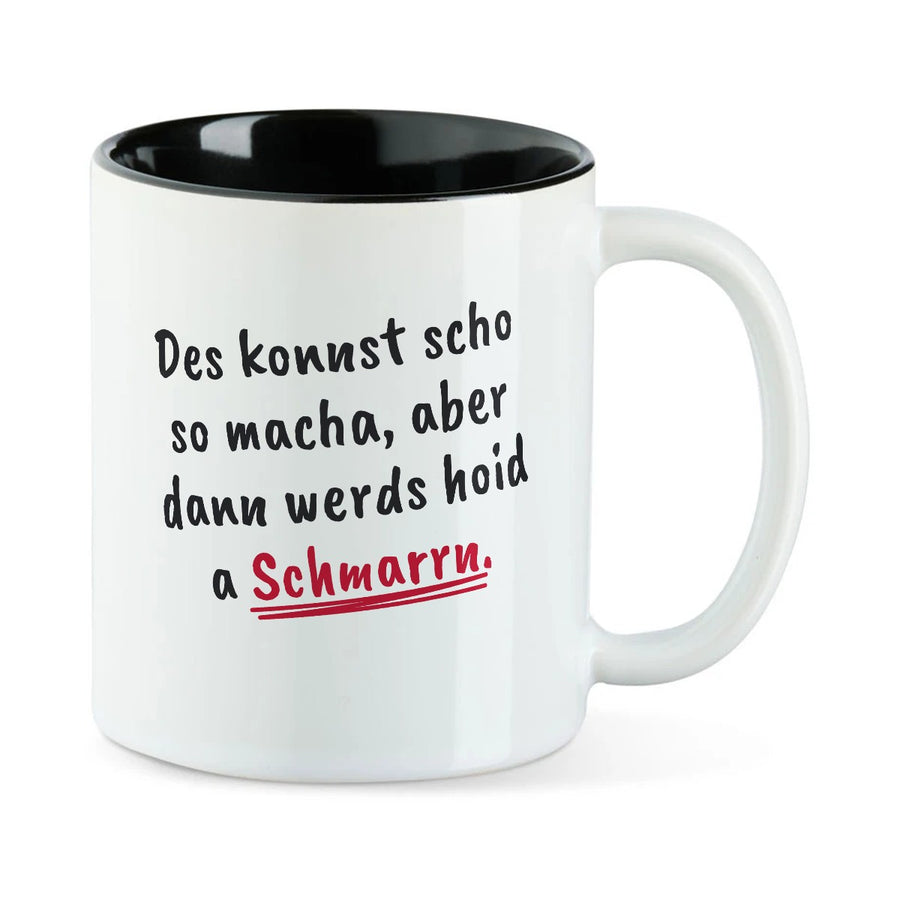 Weiße Tasse mit schwarzer Innenseite und dem bairischen Spruch „Des konnst scho so macha, aber dann werds hoid a Schmarrn.“ in Pinselschrift.