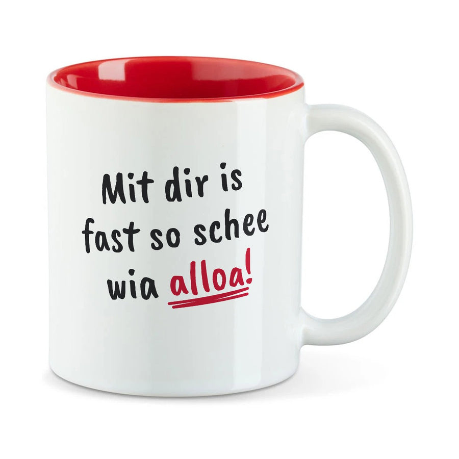 Weiße Tasse mit roter Innenseite und dem bairischen Spruch „Mit dir is fast so schee wia alloa!“ in Pinselschrift.