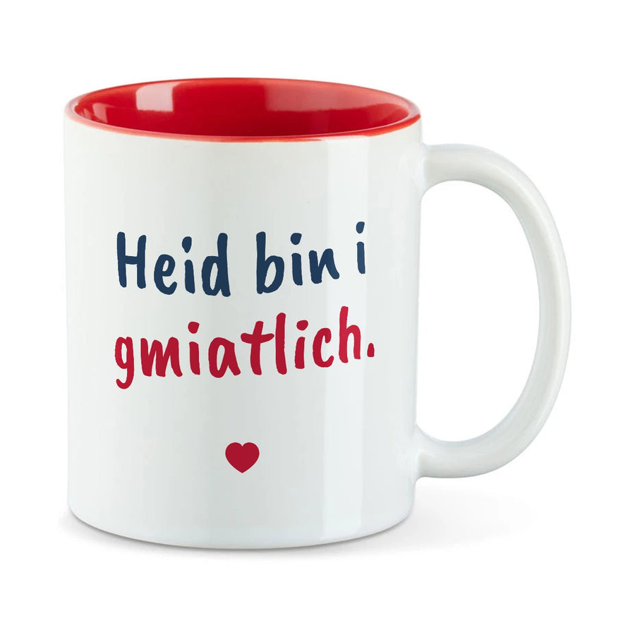 Weiße Tasse mit roter Innenseite und dem bairischen Spruch „Heid bin i gmiatlich.“ in Pinselschrift.