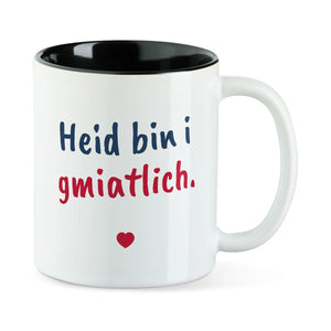 Weiße Tasse mit schwarzer Innenseite und dem bairischen Spruch „Heid bin i gmiatlich.“ in Pinselschrift.