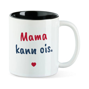 Weiße Tasse mit schwarzer Innenseite und dem bairischen Spruch „Mama kann ois.“ in Pinselschrift.
