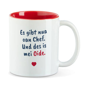 Weiße Tasse mit roter Innenseite und dem bairischen Spruch „Es gibt nua oan Chef. Und des is mei Oide.“ in Pinselschrift.