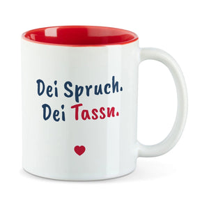 Weiße Tasse mit roter Innenseite und dem Beispielspruch „Dei Spruch. Dei Tassn.“ mit kleinem Herz darunter.