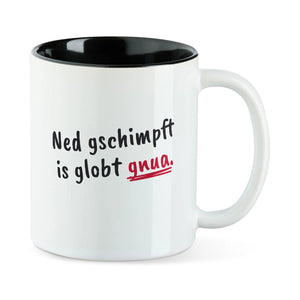 Weiße Tasse mit schwarzer Innenseite und dem bairischen Spruch „Ned gschimpft is globt gnua.“ in Pinselschrift.