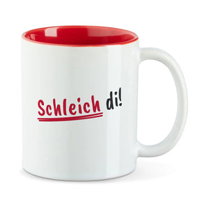 Weiße Tasse mit roter Innenseite und dem bairischen Spruch „Schleich di!“ in Pinselschrift.