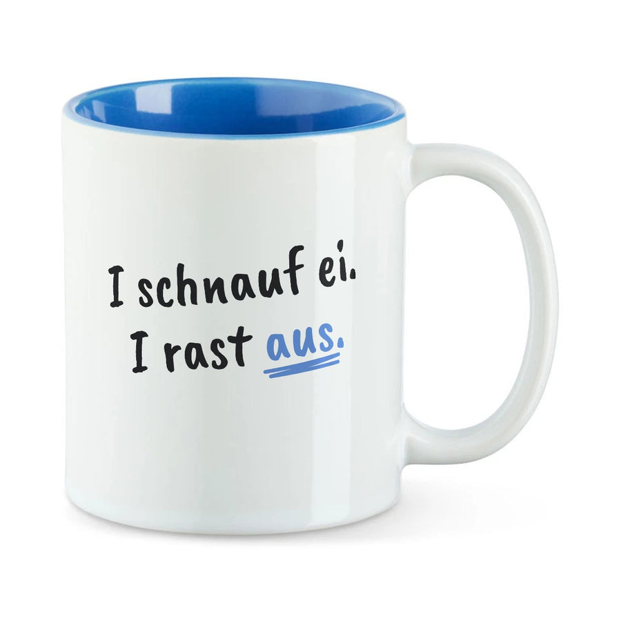 Weiße Tasse mit blauer Innenseite und dem bairischen Spruch „I schnauf ei. I rast aus.“ in Pinselschrift.