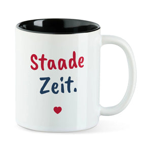 Weiße Tasse mit schwarzer Innenseite und dem bairischen Spruch „Staade Zeit.“ in Pinselschrift.