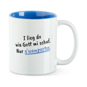 Weiße Tasse mit blauer Innenseite und dem bairischen Spruch „I lieg do wia Gott mi schuf. Nur g'wamperter.“ in Pinselschrift.